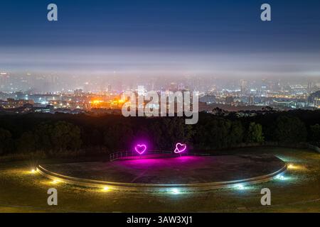 Il parco con vista notturna di Wanggaoliao al tramonto presenta sculture di cuore luccicanti che si affacciano sul paesaggio nebbioso della città di Taichung. Un luogo popolare per date e proposte Foto Stock