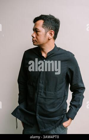 Un uomo premuroso in un abbigliamento casual guarda da parte. Ritratto di un uomo serio in piedi di fronte a uno sfondo semplice Foto Stock