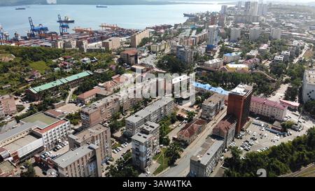 Vista aerea di una vivace città portuale, con navi da carico che attraccano vicino a un'area residenziale piena di condomini Foto Stock