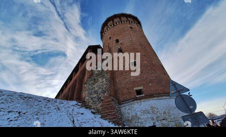 Kolomna, regione di Mosca - 4 gennaio 2025: Storica torre medievale in mattoni del Cremlino di Kolomna contro il cielo blu con una collina innevata Foto Stock