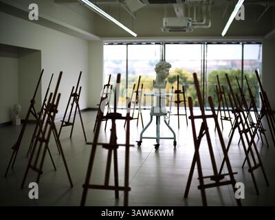 Busto in gesso su piedistallo a ruote tra cavalletti in legno nel soleggiato Studio d'Arte durante un tranquillo pomeriggio Foto Stock