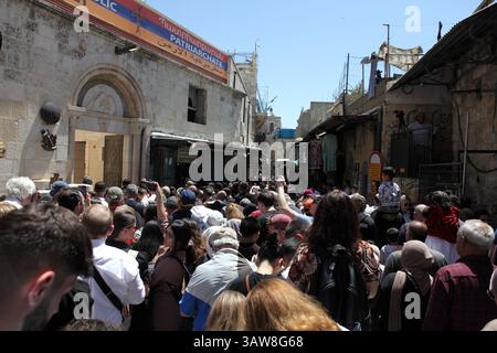 Vista posteriore di una folla di pellegrini cattolici che camminano pregando e cantando in una processione del venerdì Santo sulla via dolorosa nella città vecchia di Gerusalemme. Foto Stock