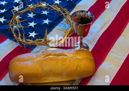 Elementi di comunione cristiana di pane e vino si trovano con una corona di spine su una bandiera americana, fondendo fede e nazionalismo cristiano. Foto Stock