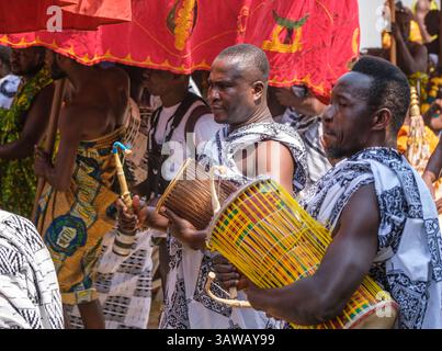 Kumasi, Ghana. Ashanti Akwasidae Festival. Gli uomini che battono tamburi nei panni di Ashanti Notables camminano in processione. Foto Stock