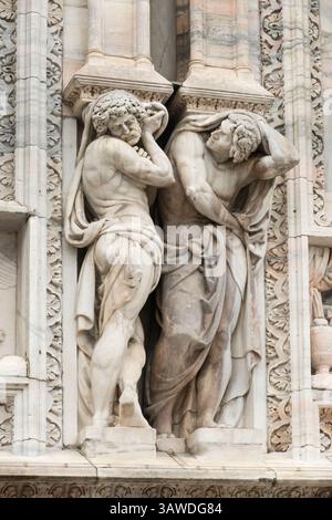 Sculture di Atlantes scolpite sulla facciata del Duomo di Milano in Italia. La costruzione iniziò nel 1386 e ci vollero quasi sei secoli per essere completata, con lavori che terminarono nel 1965. La cattedrale è una delle più grandi cattedrali gotiche del mondo. La cattedrale è realizzata in marmo bianco-rosato di Candoglia. ? Presenta oltre 3.400 statue, comprese quelle sui capitelli delle pilastri e sull'esterno. Milano, Italia Foto Stock