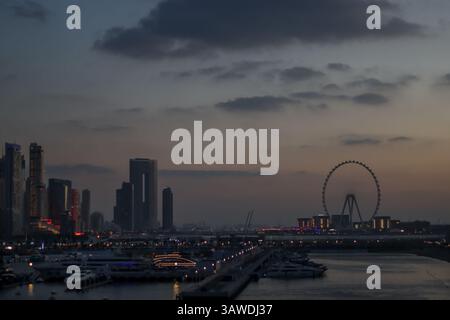 L'incantevole skyline di Dubai al crepuscolo, caratterizzato da un lungomare splendidamente illuminato con lussuose barche ancorate lungo il porticciolo. Foto Stock