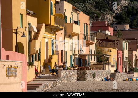 La spiaggia e l'architettura vernacolare delle proprietà fronte spiaggia della Spiaggia di Varigotti. Spiaggia di Varigotti. Persone che apprezzano le loro proprietà fronte spiaggia. Varigotti è una frazione del comune di finale Ligure, in Liguria. Foto Stock