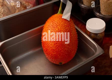 Una vista di un frutto gac crudo in una pentola metallica. Foto Stock