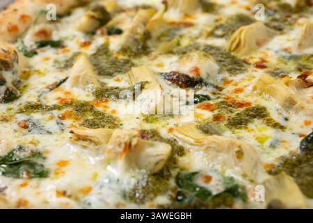 Vista di una pizza con spinaci e carciofi, come sfondo. Foto Stock
