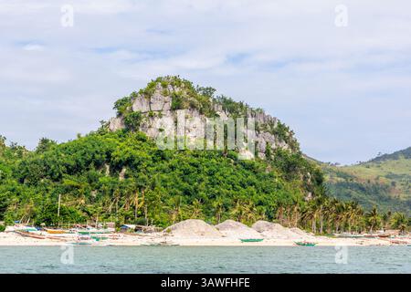 Una montagna carsica calcarea orlata di alberi sorge vicino alla spiaggia di Isla Gigantes, Iloilo, Filippine, offrendo un paesaggio costiero spettacolare Foto Stock