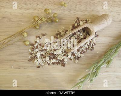 Miscela di semi con fiocchi d'avena, semi di lino e semi di sesamo su un asse di legno Foto Stock