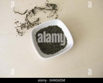 Semi di ortica essiccati con superfood, semi di ortica su un asse di legno Foto Stock