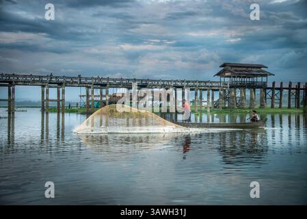 Pescatore che lancia una rete da pesca sul lago Taungthaman accanto al ponte U Bein vicino ad Amarapura in Myanmar Foto Stock