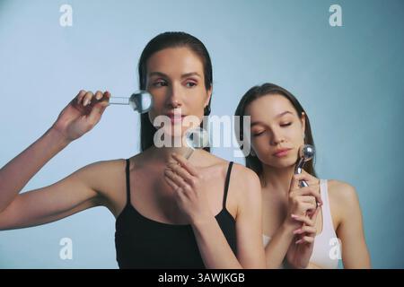 Donne che praticano tecniche per la cura della pelle con strumenti per il viso in un ambiente sereno Foto Stock