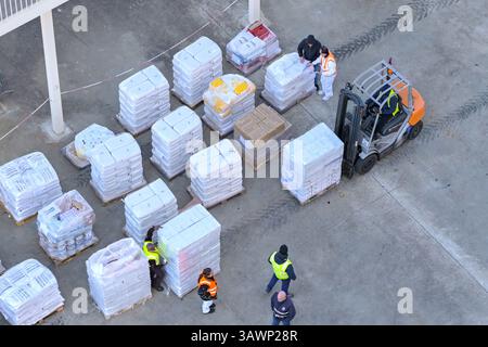 Lisbona, Portogallo - 13 gennaio 2025: Vista aerea dei lavoratori portuali che utilizzano un carrello elevatore per spostare pallet di forniture da caricare su una nave da crociera Foto Stock