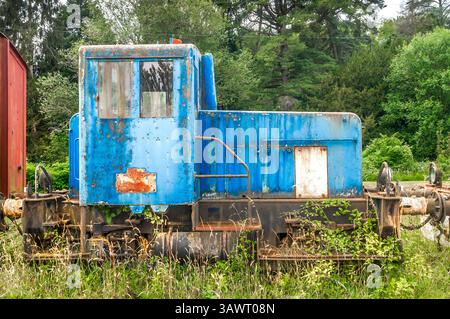 Vecchio motore di manovra diesel arrugginito nei binari ferroviari della società di conservazione per un potenziale rinnovamento. Foto Stock