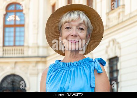 Bella donna anziana in abito blu all'aperto in una giornata di sole. Fiducia, maturità ed eleganza Foto Stock