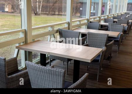 Caffetteria all'aperto con moderne sedie in vimini e tavoli in legno su una terrazza Foto Stock