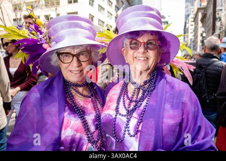 New York, New York, Stati Uniti. 20 aprile 2025. Una folla di coloratissimi e spesso fantasiosi finimenti si è rivelata in una calda giornata di primavera per l'annuale Easter Bonnet Parade and Festival di New York. Due donne più anziane vestite con abiti viola coordinati. Crediti: Ed Lefkowicz/Alamy Live News Foto Stock