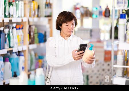 Donna anziana che esegue la scansione del codice qr per il sapone liquido Foto Stock