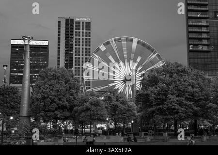 Atlanta, Stati Uniti: 19 aprile 2025: Foto in bianco e nero dello skyline del centro di Atlanta al tramonto, edifici, ruota panoramica e turisti che si godono un fresco sprin Foto Stock