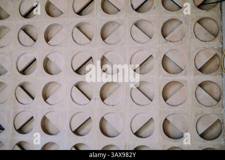 Parete architettonica in cemento. Il motivo geometrico con cerchi divisi da linee diagonali crea una superficie strutturata e moderna. Foto Stock