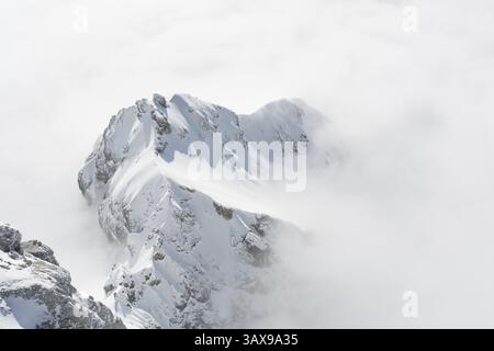 La montagna soleggiata della catena montuosa di Dachstein si distingue nel tappeto di nebbia Foto Stock