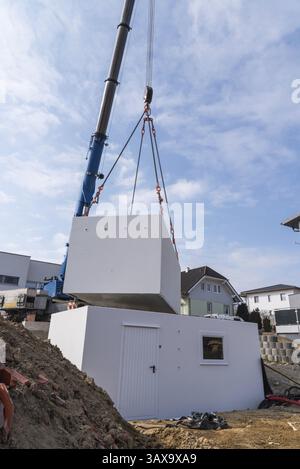 La gru da cantiere erige parti di garage - cantiere con gru Foto Stock