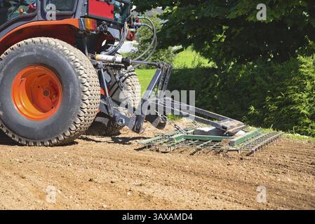 Il trattore piccolo con erpice allenta il terreno - progettazione e coltivazione del terreno Foto Stock