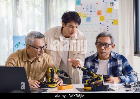 Gli ingegneri di asian robot ARM fanno brainstorming in officina per sviluppare tecnologie di controllo con lavoro di squadra e innovazione nella codifica Foto Stock