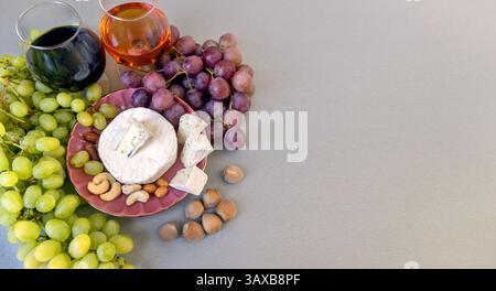 Vassoio di vini e formaggi con uva e noci. Un sofisticato piatto di vini e formaggi con due bicchieri di vino, uva verde e rossa, assortiti Foto Stock