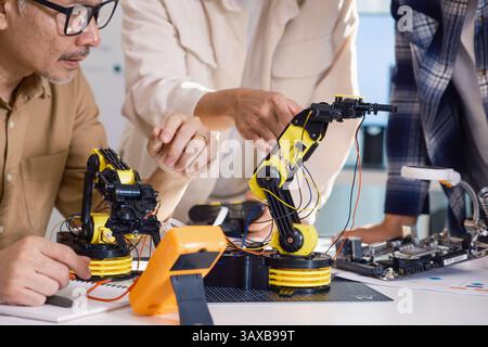 Gli ingegneri di asian robot ARM fanno brainstorming in officina per sviluppare tecnologie di controllo con lavoro di squadra e innovazione nella codifica Foto Stock