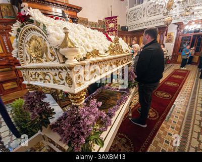 corfù, corfù, Grecia. 18 aprile 2025: Epitaphios adornato con fiori bianchi e lilla viola durante la celebrazione pasquale ortodossa. Foto Stock