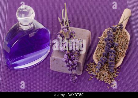 Essenza da bagno e sapone con lavanda su fondo viola essenza da bagno e sapone con lavanda su fondo viola Foto Stock