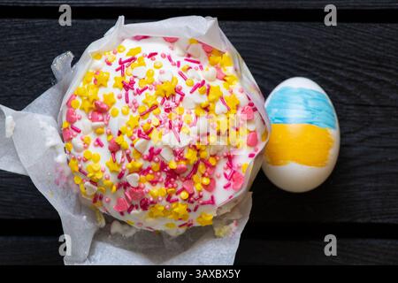 Uovo di Pasqua con bandiera Ucraina dipinta e torta di Pasqua su un tavolo di legno nero, Pasqua in Ucraina Foto Stock