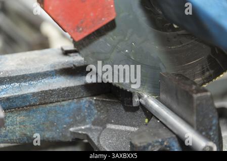 La lama di una sega circolare per metallo taglia un tubo metallico - primo piano Foto Stock