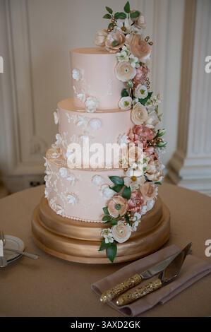 Torta floreale blush a tre livelli con base dorata Foto Stock