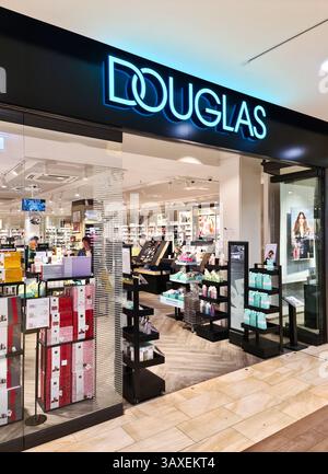 Kiel, Germania - 19. Aprile 2025: Immagine ampia di un ingresso DI un negozio DOUGLAS in un centro commerciale, con un cartello illuminato, scaffali di prodotti di bellezza e navigazione c Foto Stock