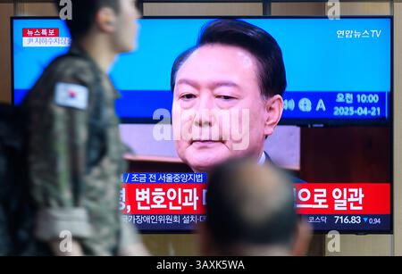 Seoul, Corea del Sud. 21 aprile 2025. La gente guarda un telegiornale Yonhap trasmesso 24 ore su 24 alla stazione ferroviaria di Seul che mostra una trasmissione di notizie con l'ex presidente della Corea del Sud Yoon Suk Yeol che partecipa alla seconda udienza del suo processo per insurrezione in un'aula del tribunale del distretto centrale di Seul a Seul. L'ex presidente Yoon Suk Yeol ha partecipato alla seconda udienza del suo processo per insurrezione il 21 aprile in quello che ha segnato la prima volta che è stato visto nel seggio dell'imputato. Credito: SOPA Images Limited/Alamy Live News Foto Stock