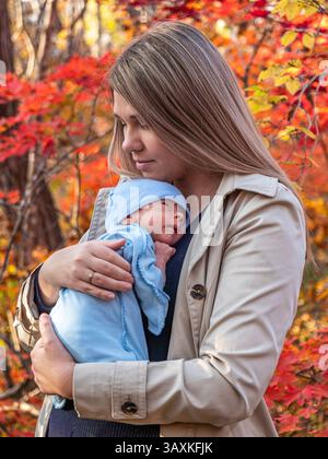 Mamma e bambino si godono un caldo abbraccio durante una splendida giornata autunnale nella foresta Foto Stock