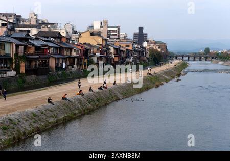 View along the Kamogawa (Kamo River) with couples sitting and relaxing on the west riverbank, a popular "lovers lane" in Kyoto, Japan. Foto Stock