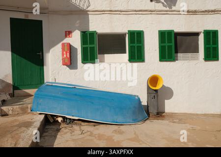 Una piccola barca blu che riposa vicino a una casa imbiancata con persiane verdi nel villaggio di pescatori di Cala Figuera, Maiorca, Isole Baleari, Spagna. Tipo Foto Stock