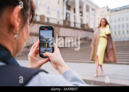 Mosca, Russia, 31.03.2025 Una donna sta facendo una foto di un'altra donna in un vestito giallo. La donna con l'abito giallo è in piedi su una scala, pos Foto Stock