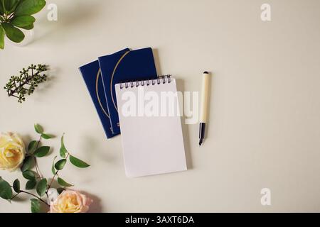 Concetto di viaggio. Composizione con passaporto, blocco note, penna, rose e foglie su sfondo bianco. modello a molla. Disposizione piatta, vista dall'alto. Foto Stock