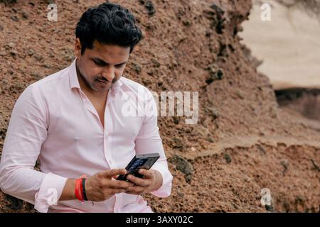 Ritratto di un uomo d'affari indiano concentrato che usa il suo smartphone all'aperto, foto con spazio di copia. Foto Stock