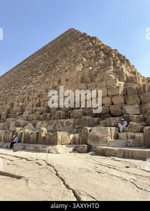 Giza, Egitto - 19 ottobre 2023: Un vecchio egiziano seduto su un blocco delle piramidi di Khufu Foto Stock