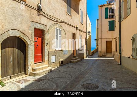 Stretta strada acciottolata fiancheggiata da vecchi e colorati edifici in pietra nella città vecchia di Antibes sulla Costa Azzurra. Foto Stock