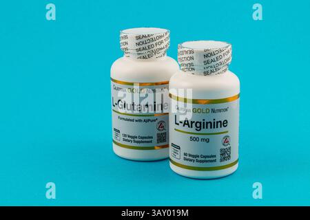 Leopoli Ucraina 10.04.25 due bottiglie di integratori alimentari sono esposte su uno sfondo blu brillante, con capsule L di glutammina e L-arginina Foto Stock