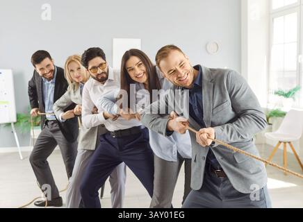 Ritratto di un giovane allegro uomo d'affari in abiti formali che tira una corda in ufficio. Foto Stock