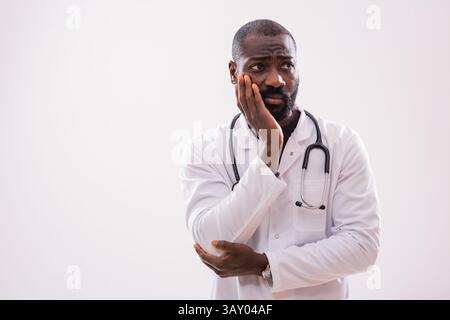 Ritratto di medico pensivo afroamericano in uniforme medica che è stanco e overworked. Foto Stock
